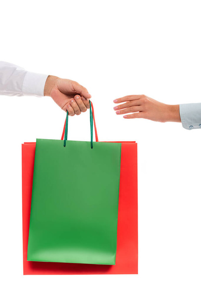 vista cortada do homem dando sacos de compras para a mulher isolada no branco  - Foto, Imagem