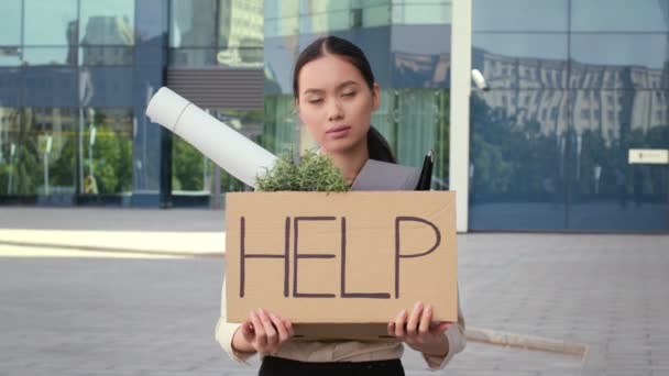 Desempleado asiático hembra celebración caja de cartón con palabra ayuda fuera - Imágenes, Vídeo