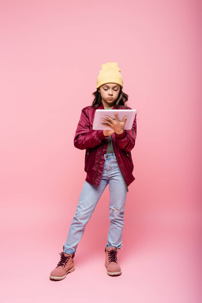 full length of stylish preteen girl using digital tablet on pink  - Photo, Image