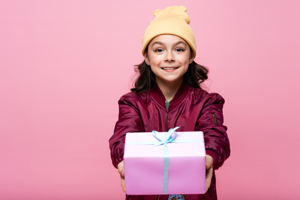 joyful preteen girl in trendy outfit holding wrapped present isolated on pink  - Fotoğraf, Görsel