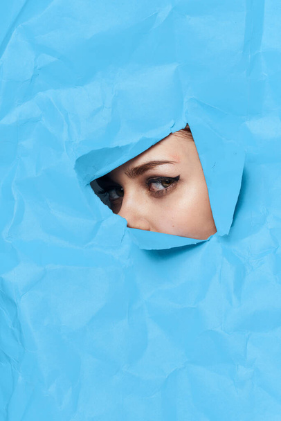 womans face breaks through blue mockup close-up - Foto, Imagem