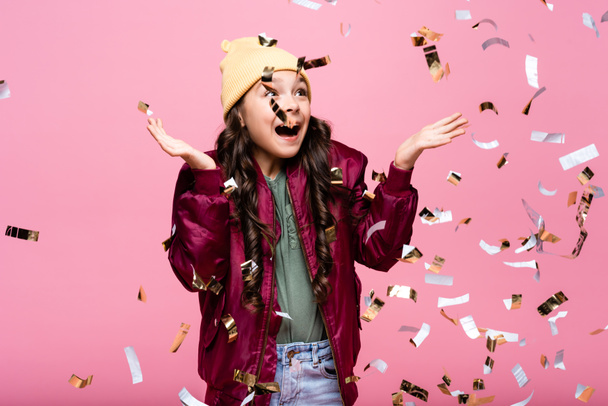 amazed preteen girl in stylish outfit smiling near falling confetti on pink  - Фото, зображення