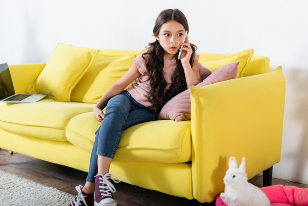 šokované preteen dívka mluví na smartphone v obývacím pokoji  - Fotografie, Obrázek