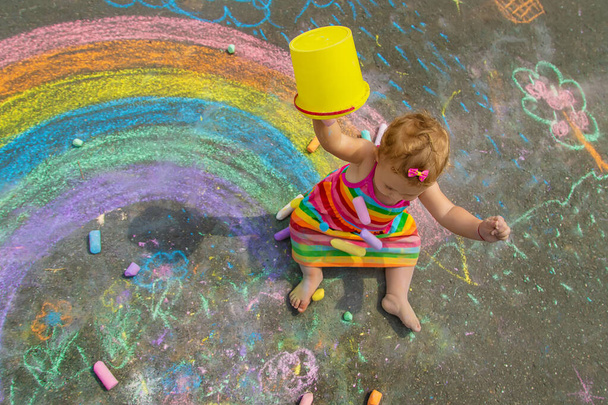 The child draws with chalk on the asphalt. Selective focus. Kid. - Fotoğraf, Görsel