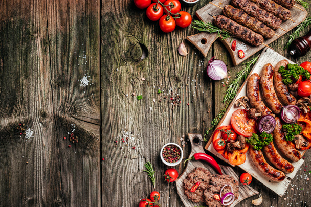Various kinds of grilled gourmet meats on a rustic wooden table. Barbecue menu. banner, menu, recipe place for text, top view. - Foto, afbeelding