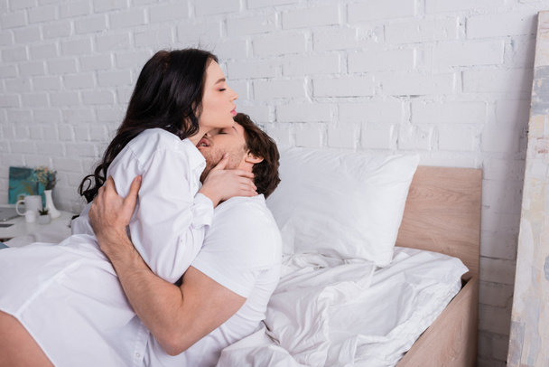 young passionate couple with closed eyes hugging in bed in morning - Foto, afbeelding