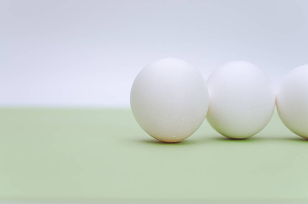 organic white eggs on a white and green surface with copy space for text - Fotografie, Obrázek