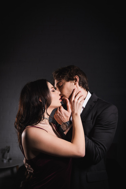 man in suit and sensual woman in elegant dress kissing with closed eyes at night - Photo, Image