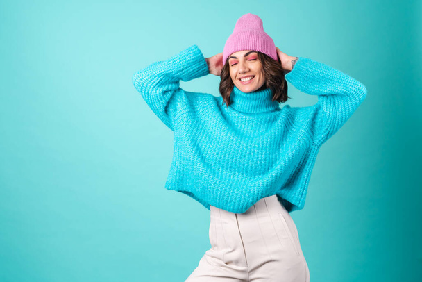 Cozy portrait of a young woman in a knitted blue sweater and a pink hat with bright makeup - Foto, imagen