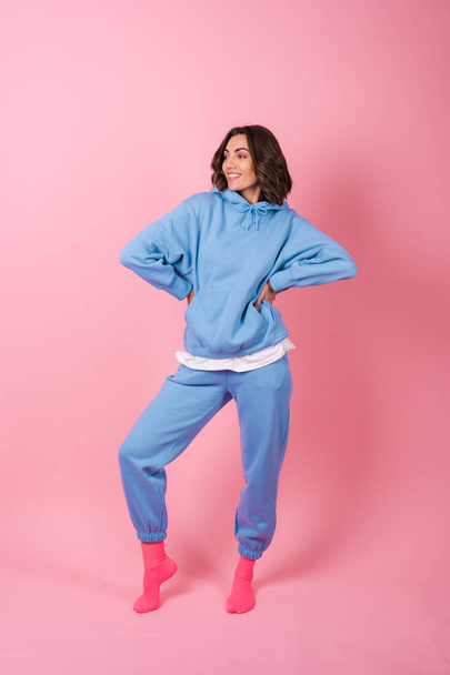 Young woman in a cozy suit on a fleece, hoodie and pants, on a pink background - Foto, imagen
