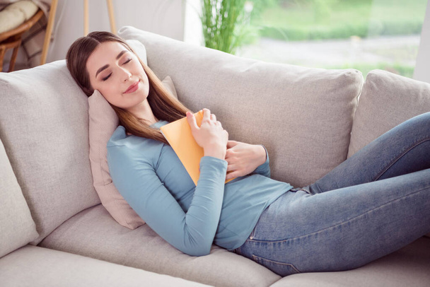 Zdjęcie portret młoda kobieta śpi na kanapie prowadzenie książki relaks w domu - Zdjęcie, obraz
