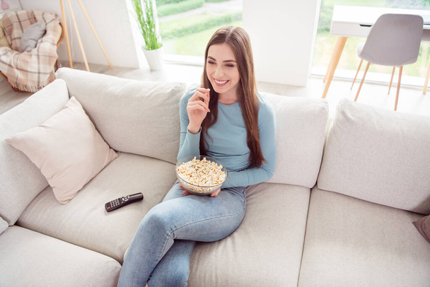 Photo of cheerful excited charming positive girl hold bowl pop corn watch cinema wear blue shirt home indoors - Fotoğraf, Görsel