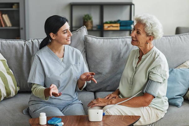 Fiatal nővér beszél idősebb nővel az idősek otthonában. - Fotó, kép