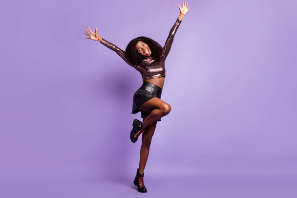 Photo of cheerful lady dance raise hands open mouth wear glossy shirt short skirt footwear isolated purple color background - Fotoğraf, Görsel