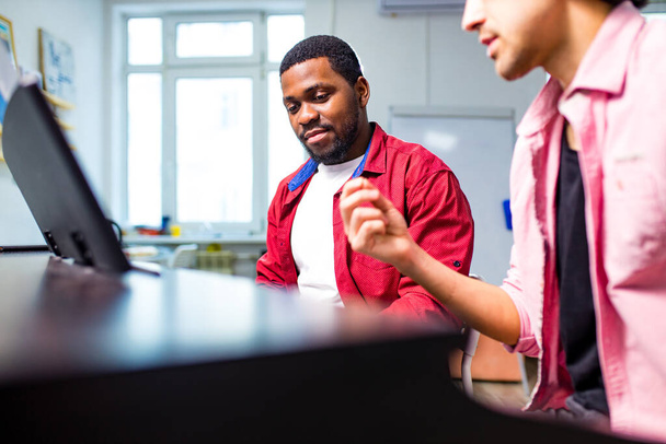 latin hispanic man learning to play on piano with caucasian teacher in classroom - Foto, imagen