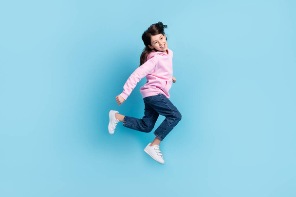 Full length body size profile side view of pretty cheerful girl jumping having fun isolated over bright blue color background - Photo, Image