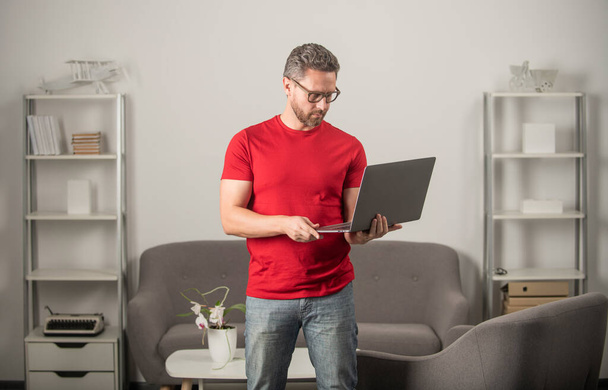 Gözlüklü olgun bir adam internette bilgisayar ve eğitim kullanıyor. - Fotoğraf, Görsel