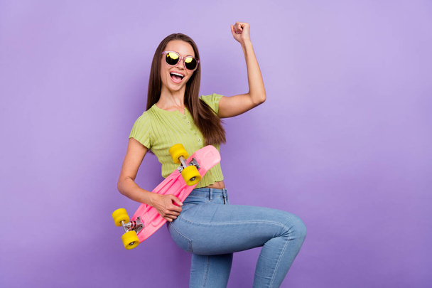 Portrait of attractive lucky cheerful girl holding skate rejoicing isolated over purple violet color background - Фото, зображення