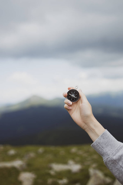 Traveler hand holds a compass on the beautiful Carpathian mountains during vacation. Horizontal banner with place for text. Technology interenet and travel adventure concept. - Photo, Image