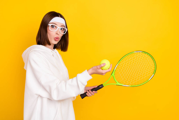 Profile side view portrait of attractive amazed girl fan amateur playing tennis isolated over bright yellow color background - Foto, immagini