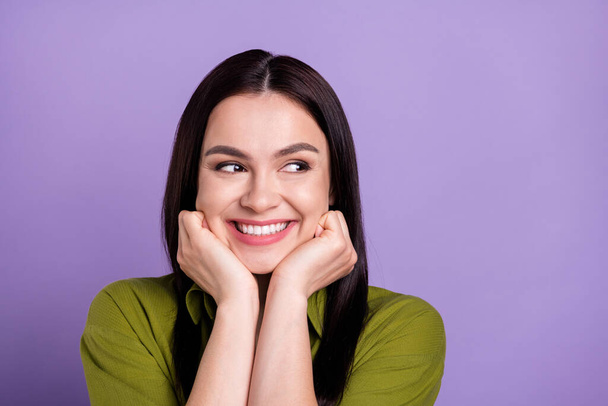 Photo of excited sweet young lady dressed green clothes smiling arms cheekbones looking empty space isolated purple color background - Foto, Imagen