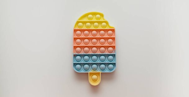 Морозиво Поп це іграшкова антистрес для дітей і дорослих на сірому фоні
 - Фото, зображення