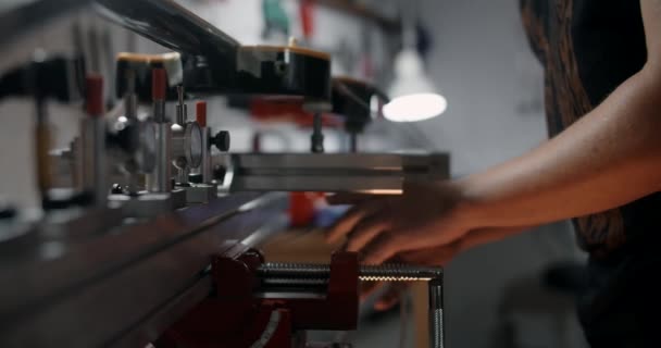 Luthier montuje gitarę elektryczną na przyrządzie w warsztacie naprawczym instrumentów muzycznych, 4k 60p 10 bit - Materiał filmowy, wideo