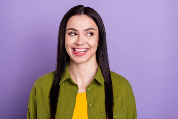 Photo of funny tricky young lady dressed green clothes smiling licking lips looking empty space isolated purple color background - Fotó, kép
