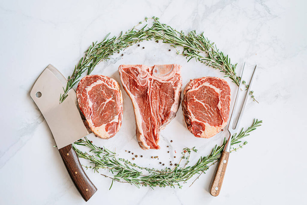 three delicious steaks ready to grill on a white marble surface - Fotografie, Obrázek