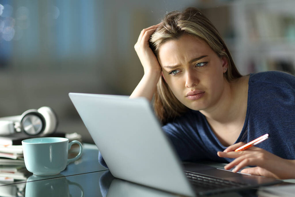 Frustrated student e-learning with a laptop in the night at home - 写真・画像