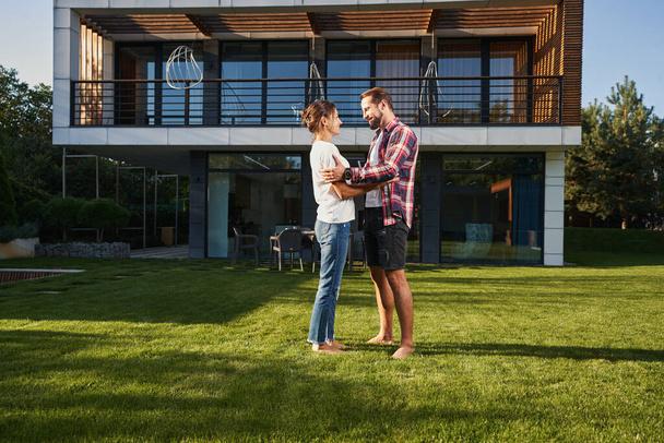 Bearded man talking with charming Caucasian female in front of the modern house - Foto, afbeelding