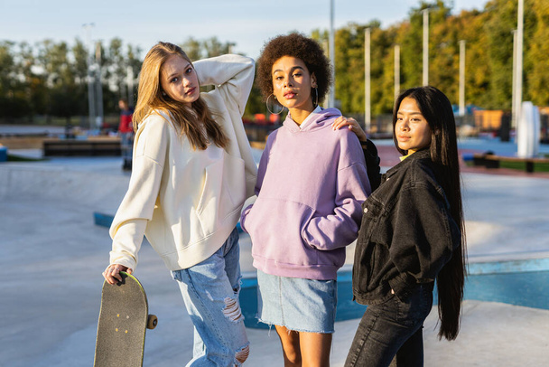 Multicultural group of young friends bonding outdoors and having fun - Stylish cool teens gathering at urban skate park - Foto, afbeelding