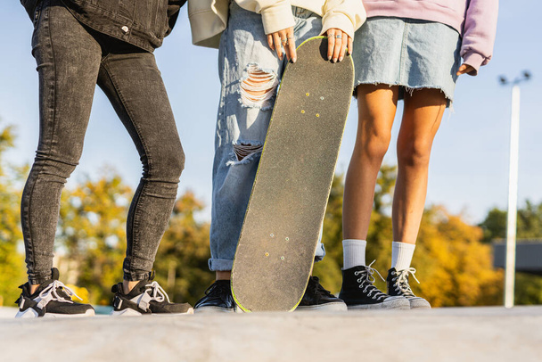 Multicultural group of young friends bonding outdoors and having fun - Stylish cool teens gathering at urban skate park - Foto, Imagen