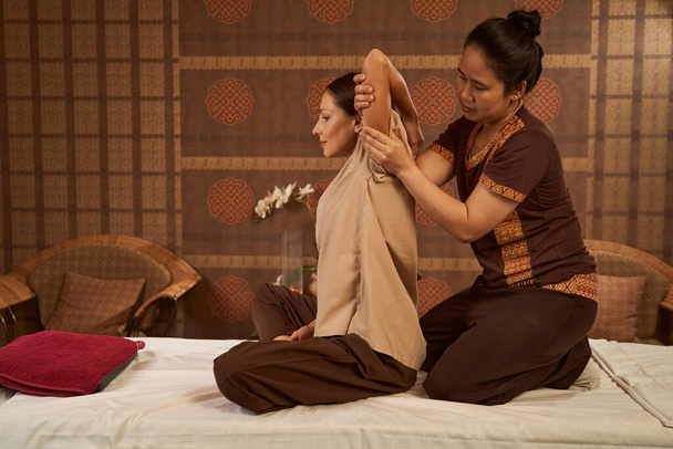 Serene spa client getting Thai stretching massage - Foto, afbeelding