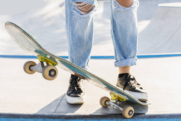 Stylish cool teen female skateboarder at skate park, close-up on shoes - Fotó, kép