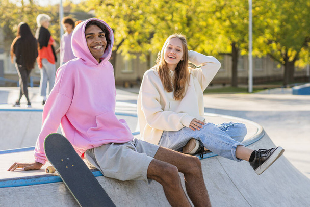 Multicultural group of young friends bonding outdoors and having fun - Stylish cool teens gathering at urban skate park - Фото, зображення