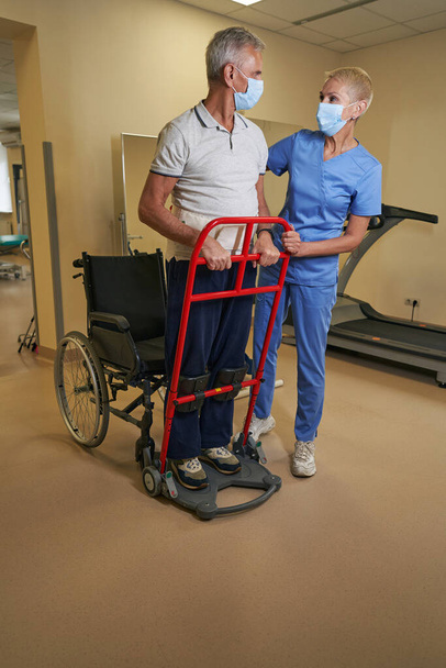 Профессиональный терапевт, работающий со зрелым мужчиной в реабилитационном центре - Фото, изображение