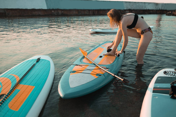 Femme athlétique pagayant sur un SUP se trouve planche à pagaie en mer bleue le jour de l'été - Photo, image