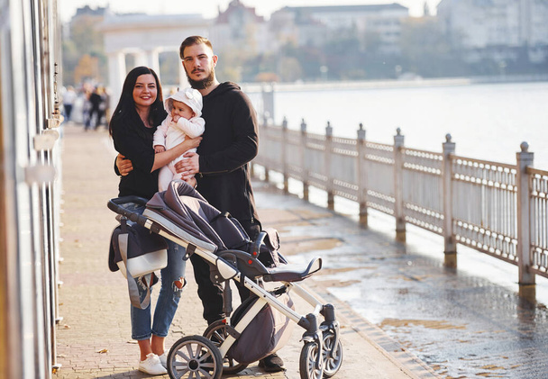 Cheerful family with pram have a walk together with their child in the park. - Фото, зображення