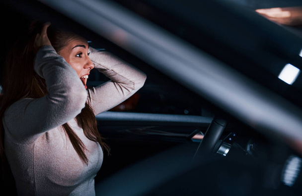 Side view of young woman that gestures inside of brand new modern automobile. - 写真・画像