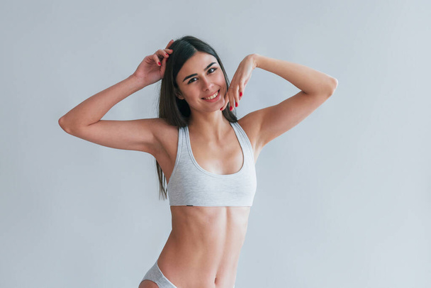 Young beautiful brunette in underwear is indoors in the studio against white background. - Fotó, kép