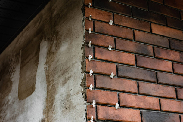 Installation des tuiles sous forme de briques sur le mur à l'aide de croix en plastique entre les tuiles. - Photo, image