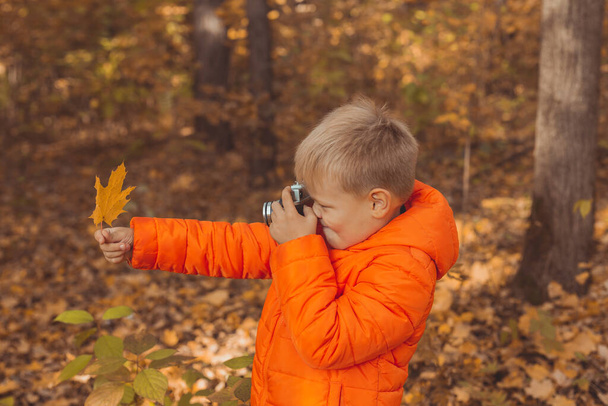 Chłopiec z aparatem retro robienie zdjęć na świeżym powietrzu w jesiennej naturze. Koncepcja czasu wolnego i fotografów - Zdjęcie, obraz