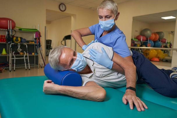 Физиотерапевт помогает пациенту с инсультом в реабилитационном центре - Фото, изображение