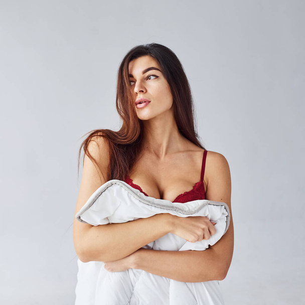 Woman in red underwear covering her body by towel in the studio against white background. - Fotoğraf, Görsel