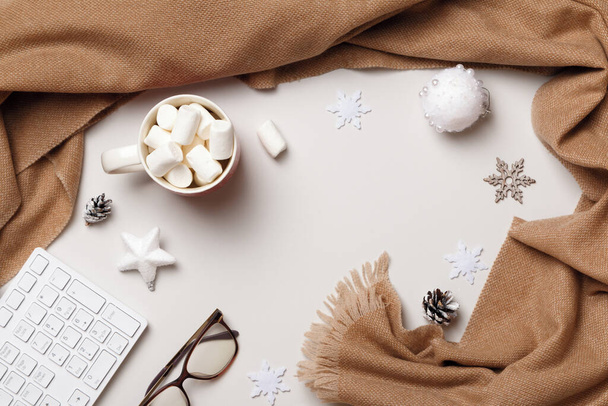 Winter desktop. New Year Christmas composition. Scarf keyboard glasses marshmallows on a white background. Flat lay top view - Фото, зображення