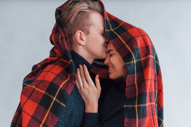 With red towel. Cute young couple embracing each other indoors in the studio. - Foto, Imagen