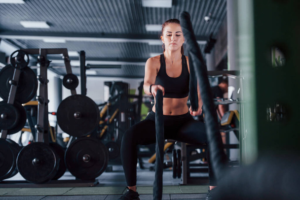 Young girl in sportive clothes is in the gym at daytime. - 写真・画像