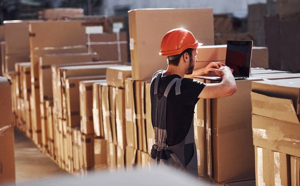 Storage worker in uniform and notepad in hands checks production. - Φωτογραφία, εικόνα