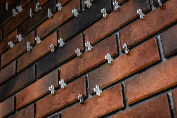 Instalación de las baldosas en forma de ladrillo en la pared utilizando cruces de plástico entre las baldosas. - Foto, imagen